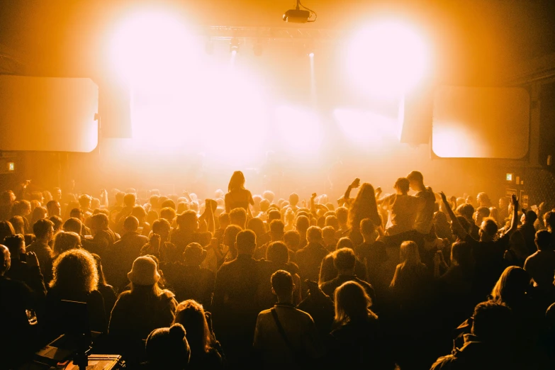 a large group of people gathered in front of bright lighting at an event