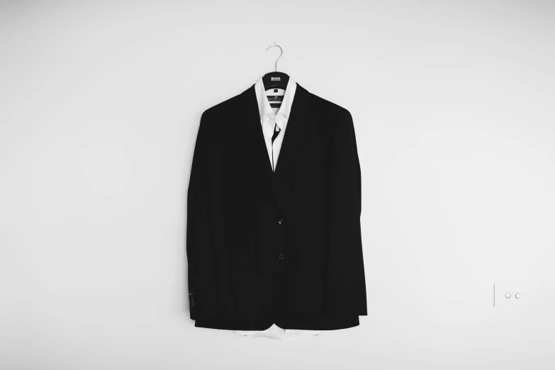 a men's black suit jacket hangs on a wall