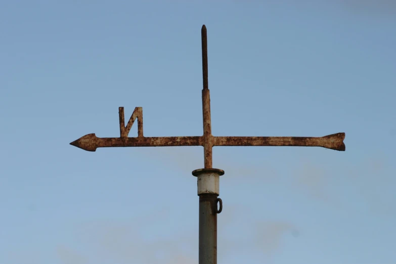 there is a rusted metal sign pointing to the sky