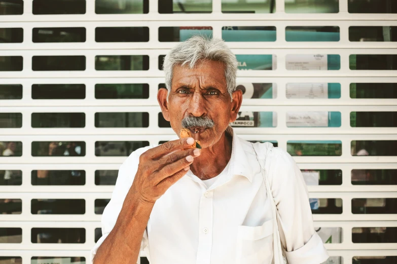 a man in a white shirt is eating a piece of food