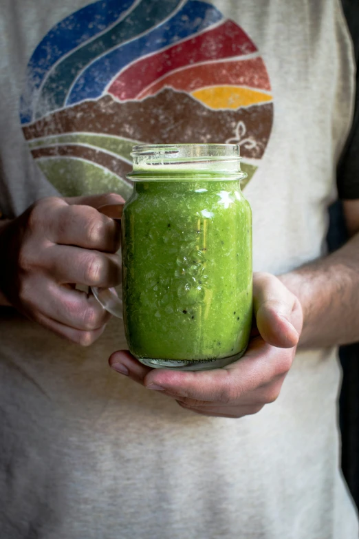 a person holding a jar filled with green liquid