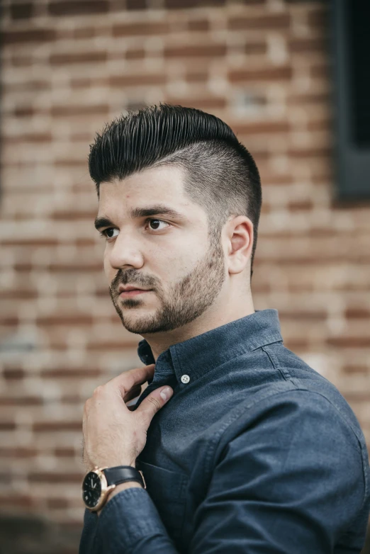 man wearing black jacket leaning on brick wall