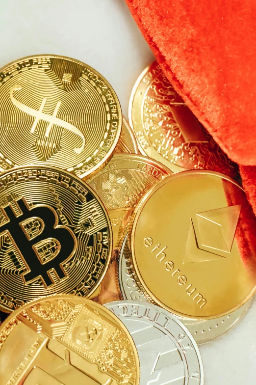 gold bitcoins and red velvet throw on white surface