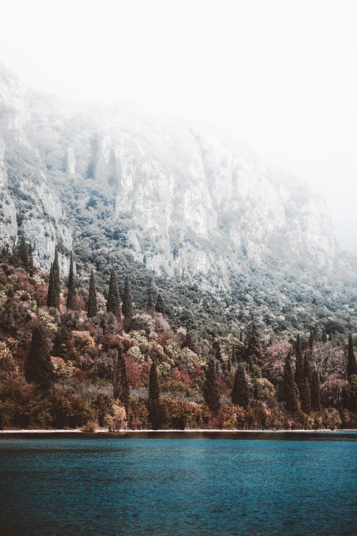 a large hill next to a lake on a cloudy day