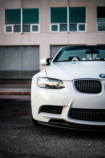 a white bmw coupe parked in front of a building