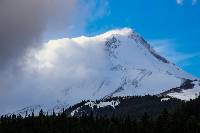 the snow - capped summit of a mountain under a cloudy sky