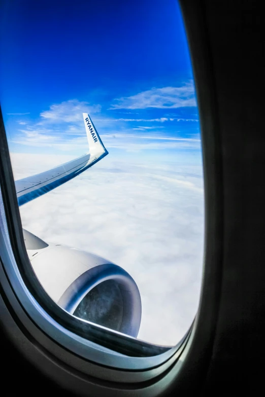 an airplane window looking at the wing and clouds