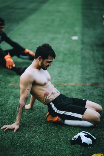 an athletic shirtless man sits on the field