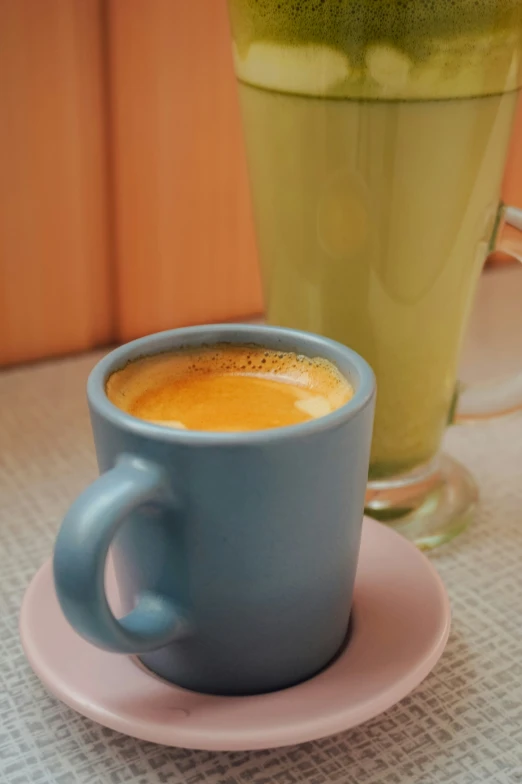 blue cup of coffee on a plate next to a tall glass