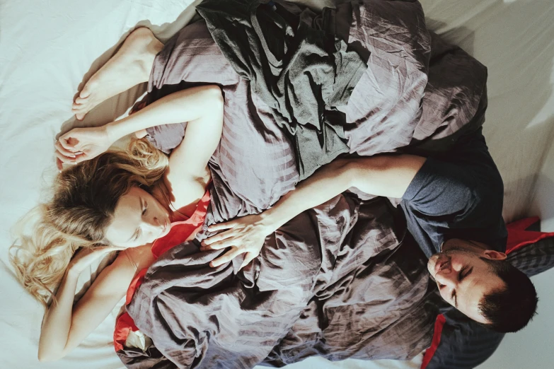 a young man and woman are laying in bed with one another