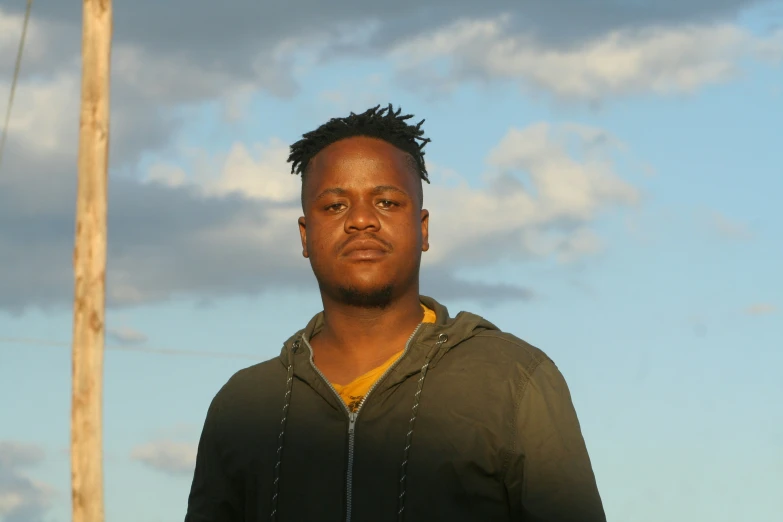 man standing next to power pole with sky and clouds