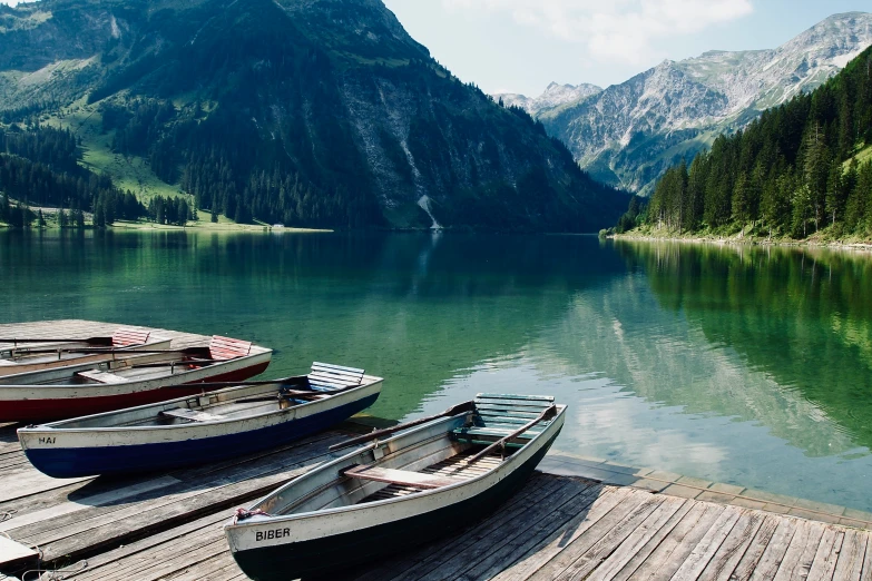 three canoes parked on the pier near a mountain lake