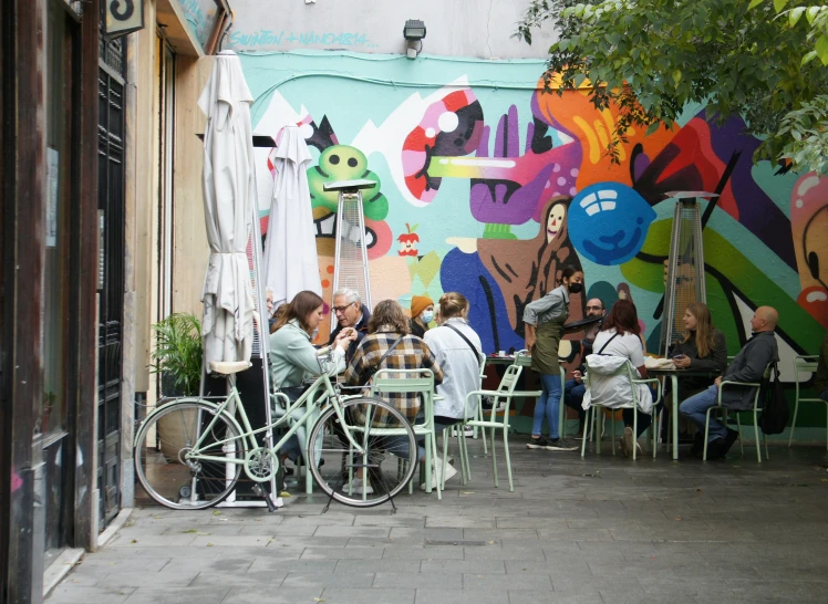 group of people sitting at tables in front of a colorful mural