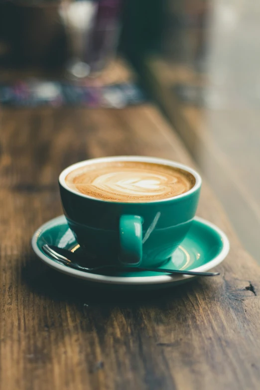 a cup and saucer with coffee sitting on a table