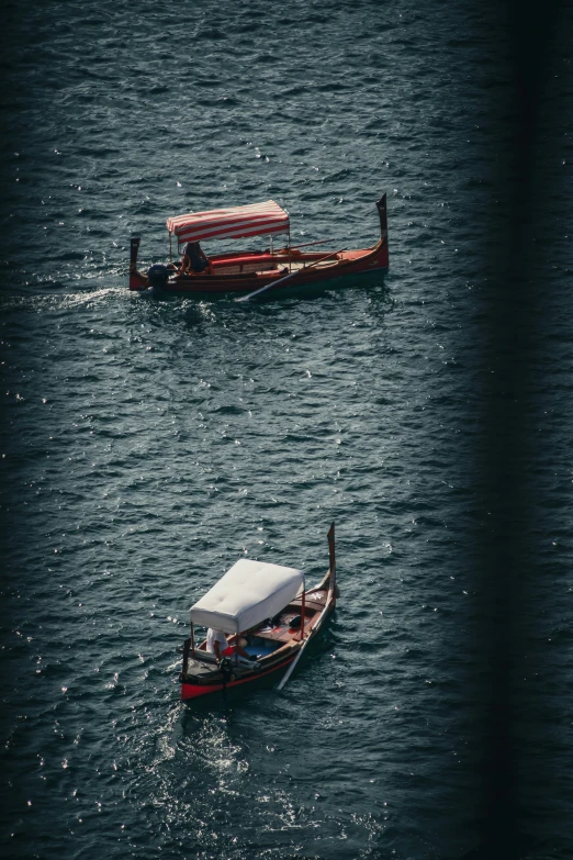 two small boats in the water one with a red and white cover on top