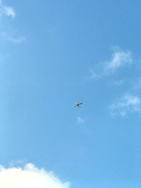 an airplane flying high in the sky, with blue clouds