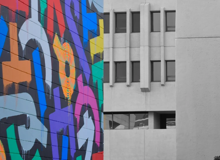 a colorful painting next to the side of a tall building