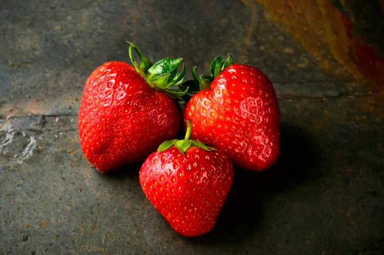 three strawberries with their leaves still on their stems