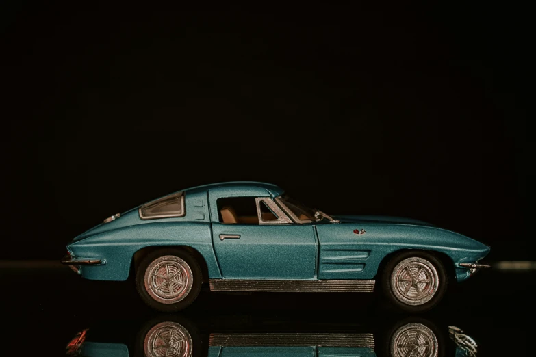 an old blue car sits on a black surface