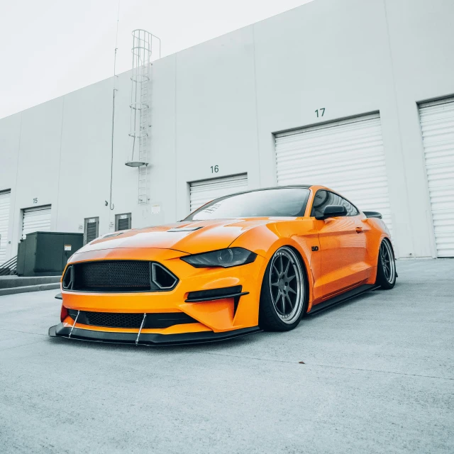 an orange car is sitting in front of a white building