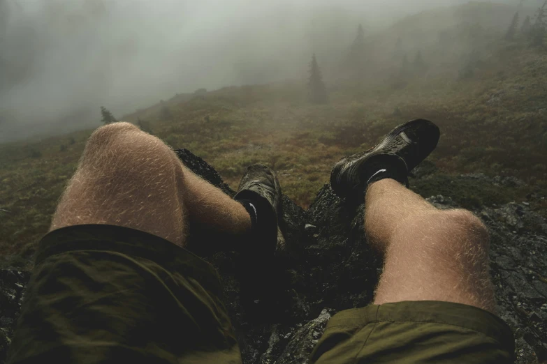 the man is sitting in the foggy mountain trail