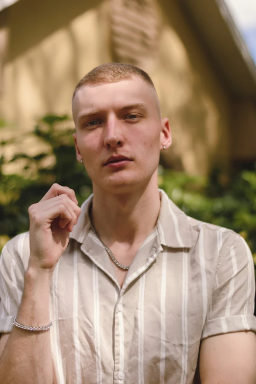 man in tan striped shirt leaning on wall