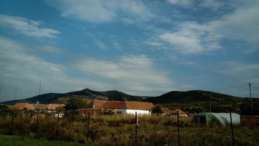 a house sits in the background near a field