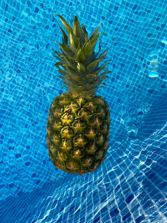 a pineapple swimming in a pool with blue water