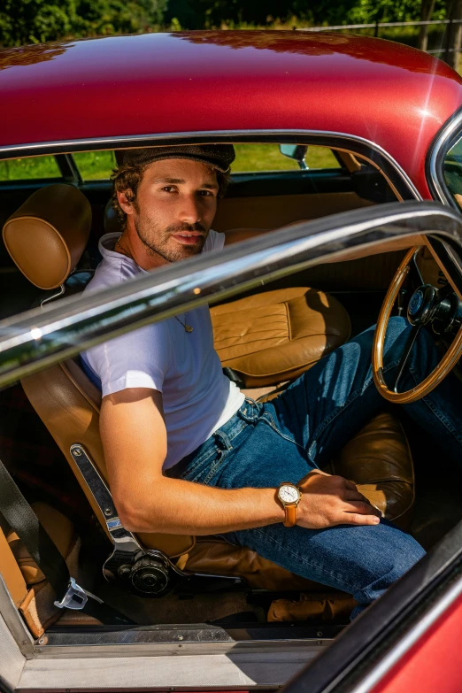 man sitting in the driver seat of an older car