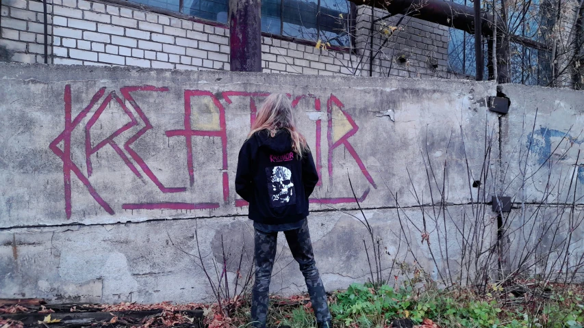 a  stands alone in front of a building with graffiti