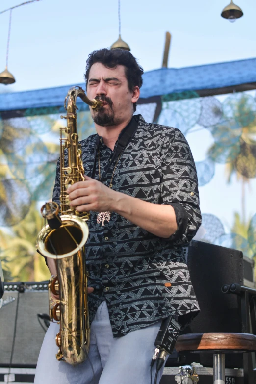 man playing saxophone on stage with palm trees