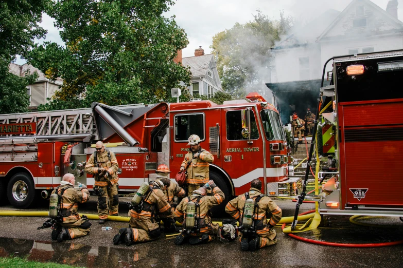 firefighters are standing outside of a building while others watch