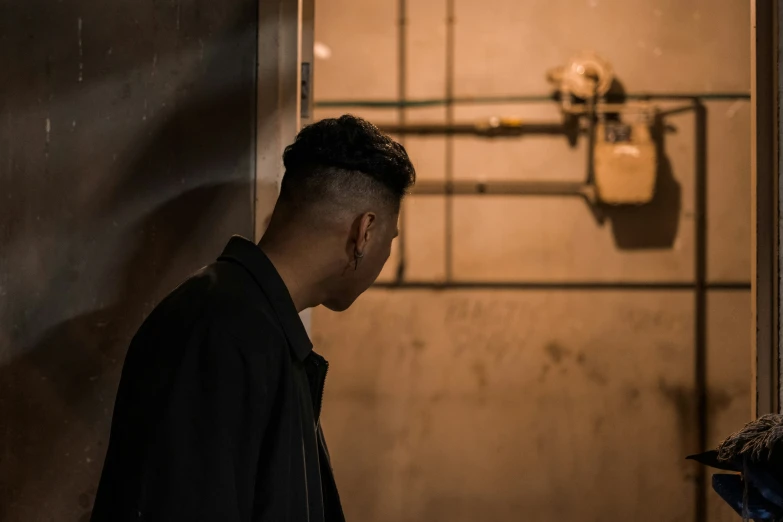 man in dark room next to wall with exposed light fixture