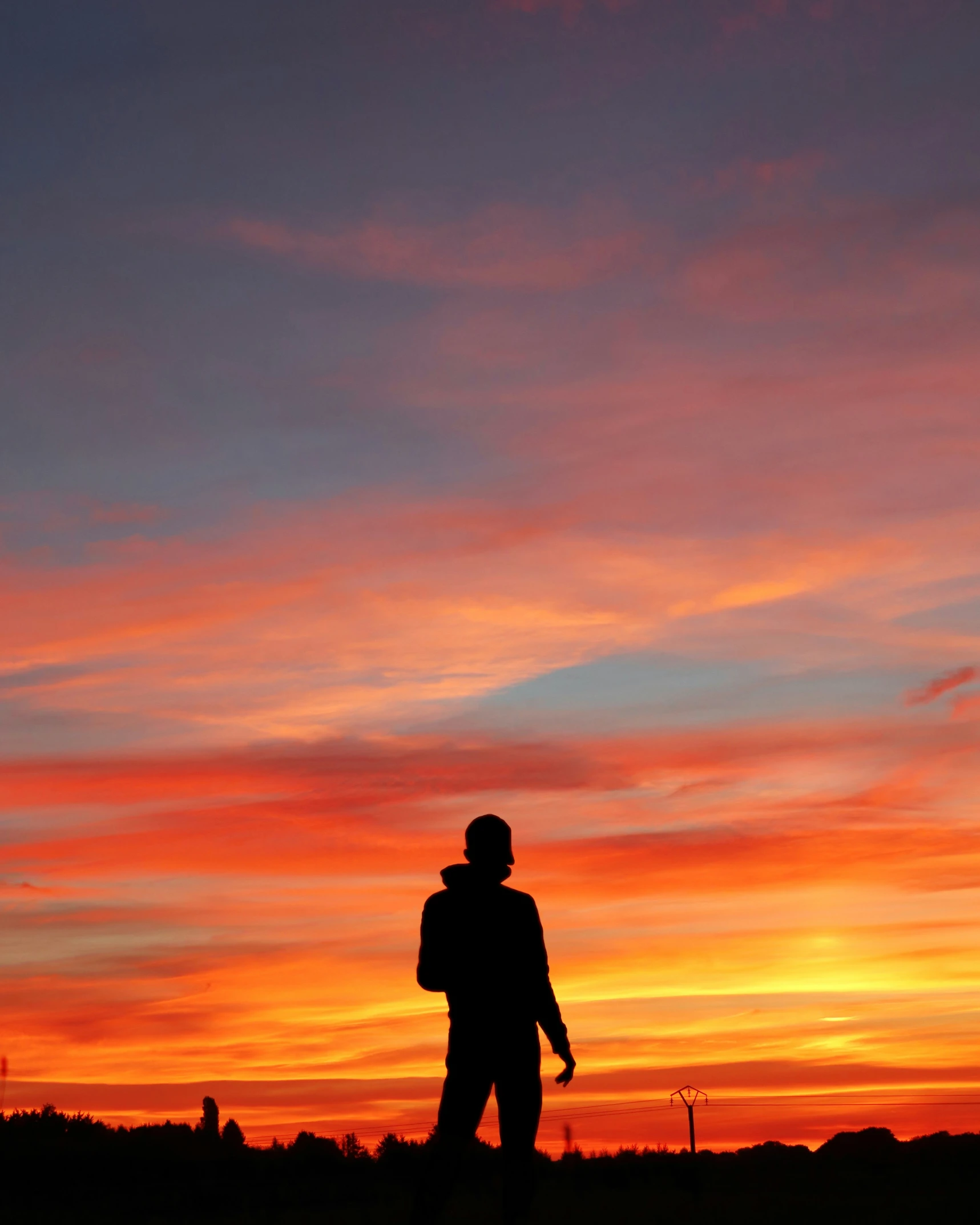 a silhouette of a man in an orange sky with a frisbee