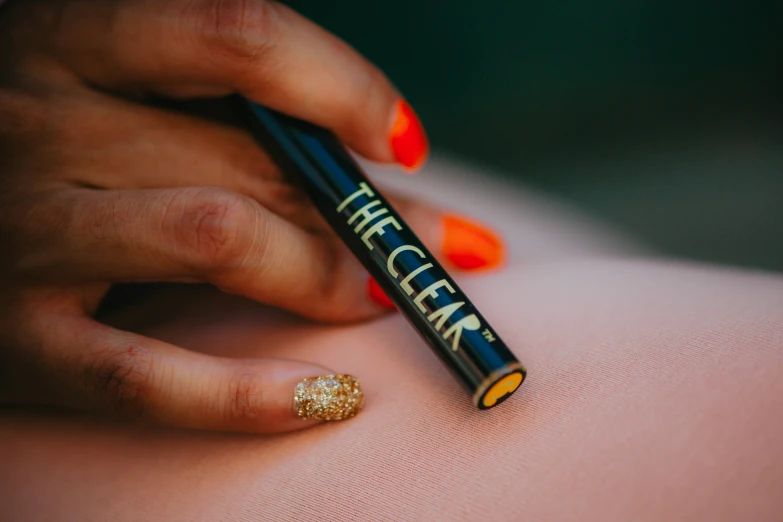 a woman holding an orange colored marker next to her stomach