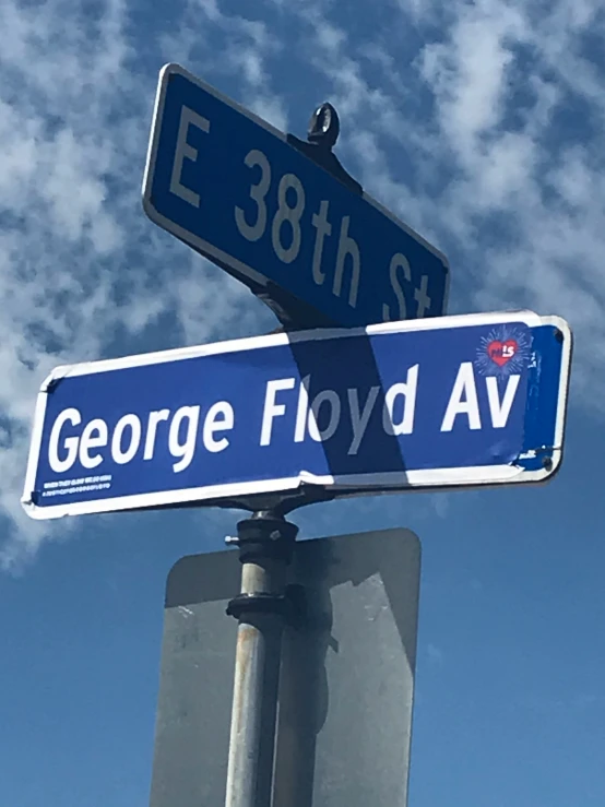 street sign with two intersecting blue signs and a blue sky background