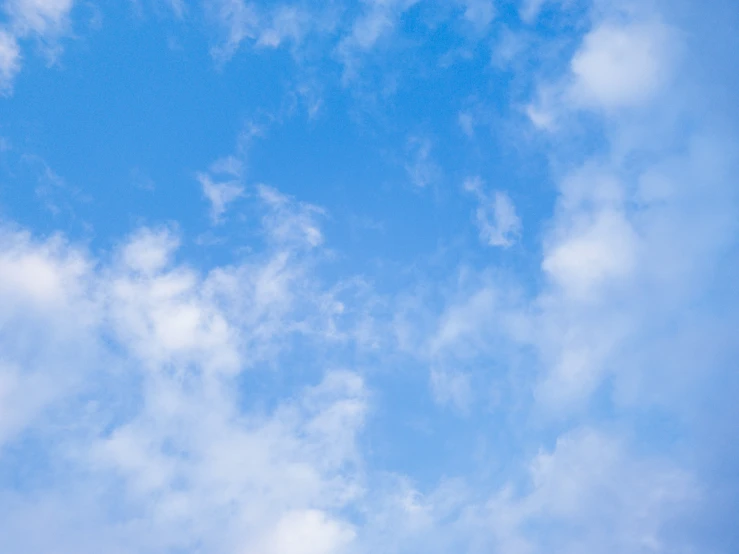 a blue sky with some clouds and an airplane flying overhead