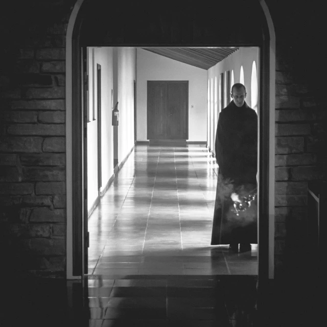 a man standing in a room holding a large bag