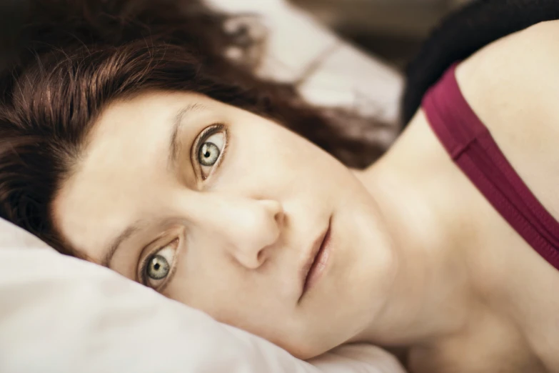 a woman laying in bed staring at the camera
