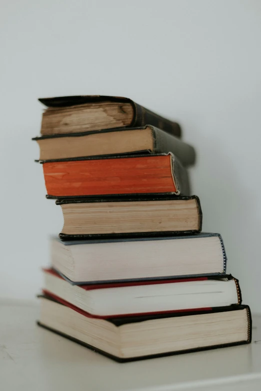 a stack of books on top of a white shelf