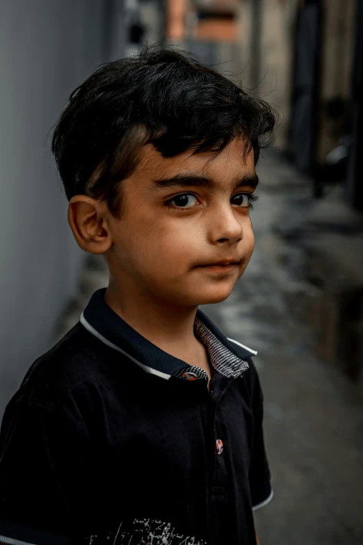 a small boy with black hair looking away