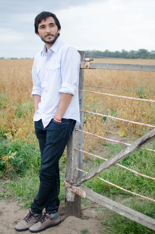 a man standing near a fence in front of tall grass