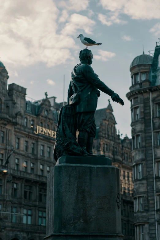 there is a statue in front of a building with a bird sitting on it