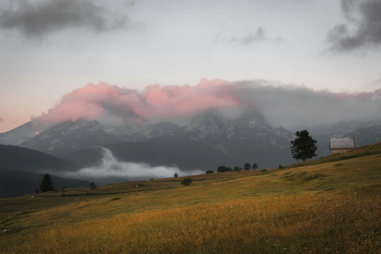 clouds are hovering over a mountain range during dusk