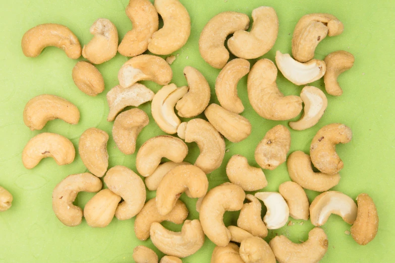 several raw cash nuts lying on a green surface
