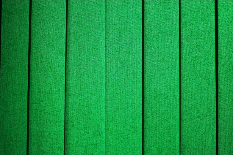 a green cloth texture with a small piece of scissors in the middle