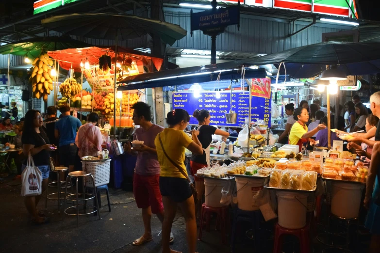 a crowded open air market has fruit and food available