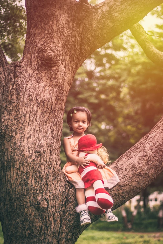 little girl sitting on tree nch with teddy bear in hands