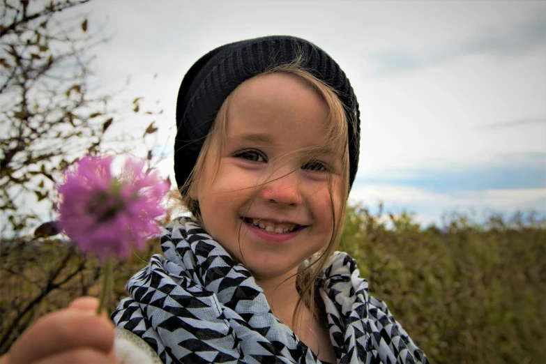 a little girl is holding a piece of purple flowers