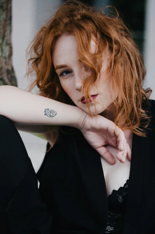 a young red - haired woman poses for a po in her black outfit